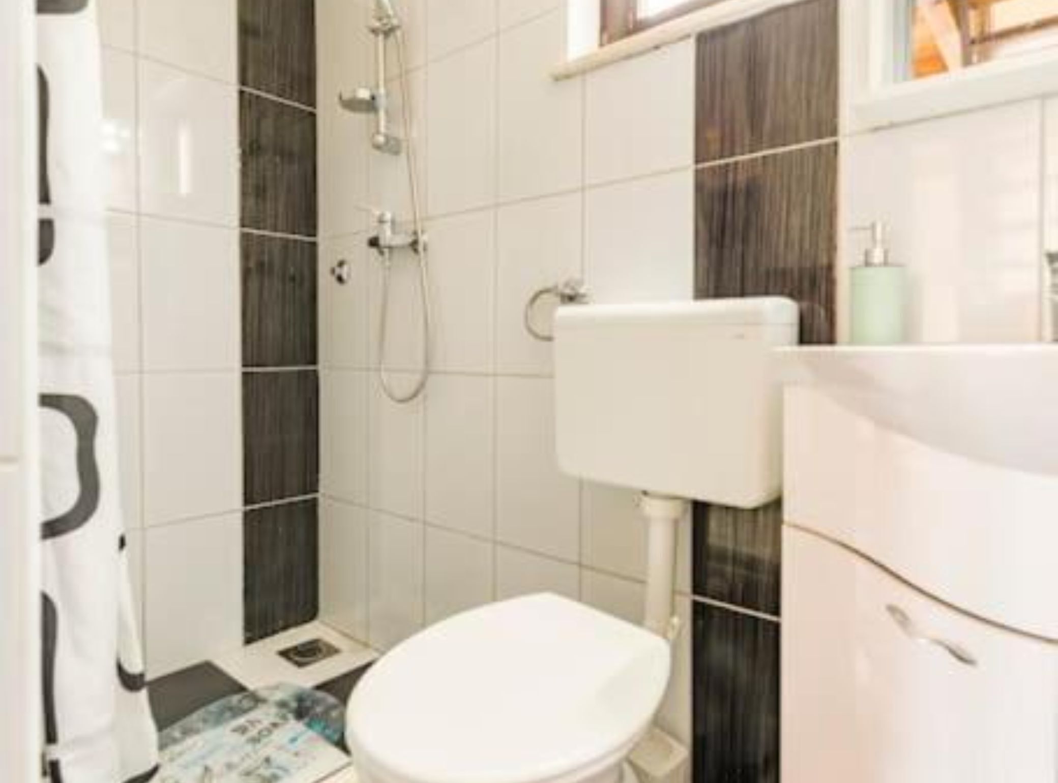 A bathroom with a toilet, a shower, and a sink.