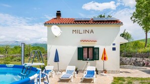 Une villa appelée MILINA, dotée d’une piscine, de chaises longues et offrant une vue sur les montagnes.