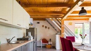 Une cuisine équipée d’appareils électroménagers modernes, un coin repas avec des chaises rouges et un plafond en bois.