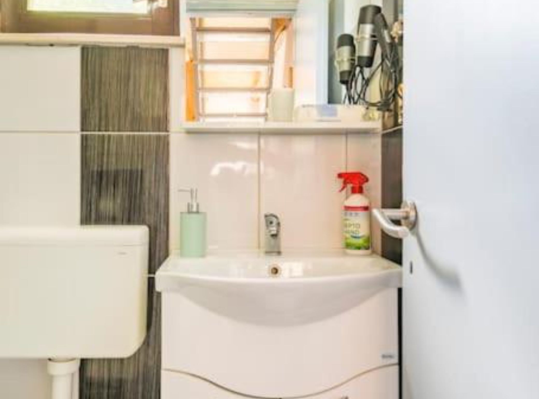A bathroom with a white sink, a bottle of hand sanitizer, and a towel rack.