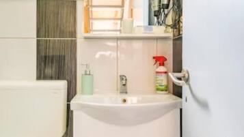 A bathroom with a white sink, a bottle of hand sanitizer, and a towel rack.