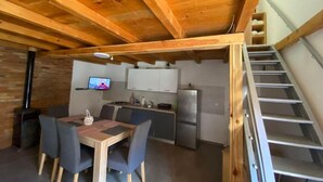 Une cuisine compacte avec des poutres en bois, un coin repas avec une table et des chaises, et un escalier.