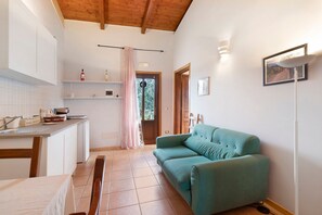 A kitchen with white cabinets, a dining table, and a teal sofa. - Annex with Wi-Fi and Air Conditioning (Montegrosso)