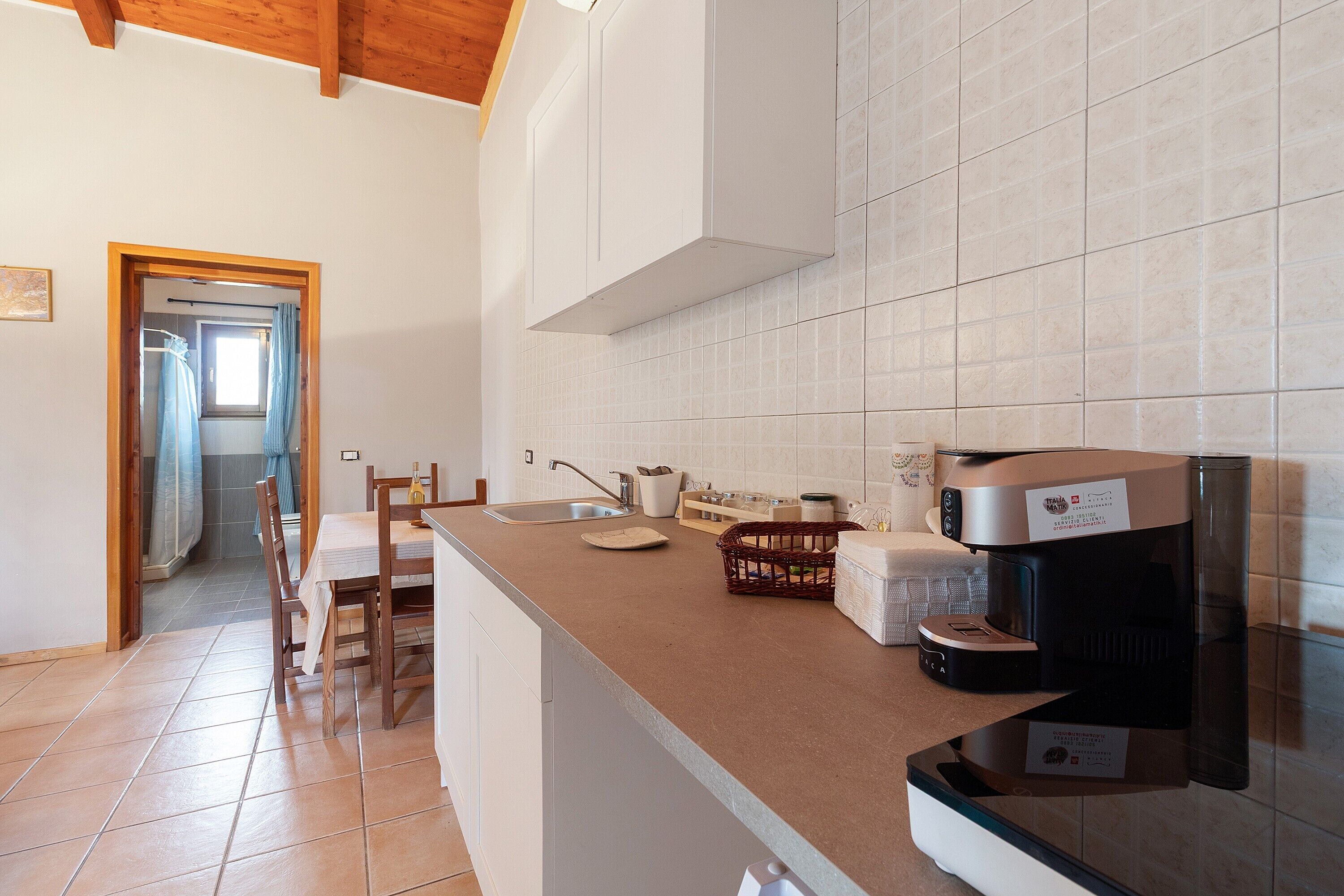 Una cucina con macchina da caffè, lavello e zona pranzo con sedie.