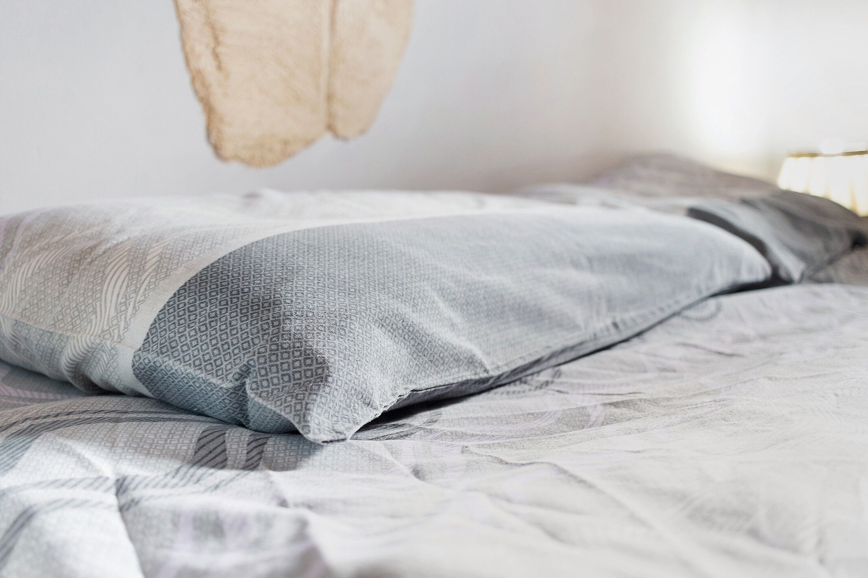 A bed with a patterned blanket and pillows.