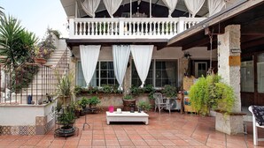 A courtyard with a balcony, potted plants, a white bench, and a stone pillar. - Terrace with Private Terrace, Wi-Fi and Air Conditioning (Montegrosso)