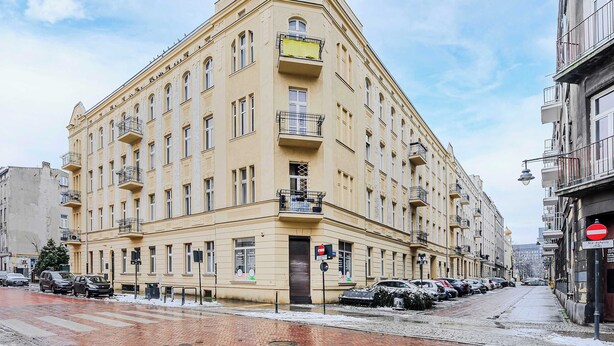 A multi-story building with a classic architectural style, featuring balconies and large windows. - Lumina bright apart near the city center (Łódź)
