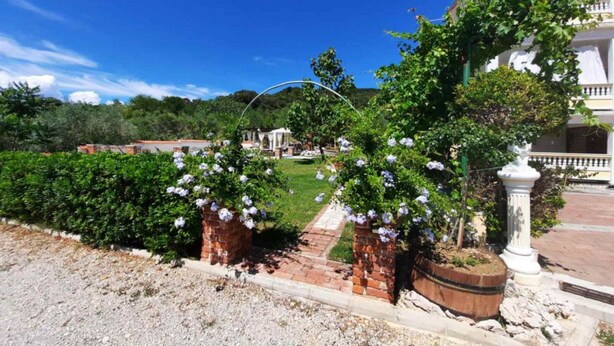 Un jardín con un sendero que conduce a un edificio blanco con balcón.