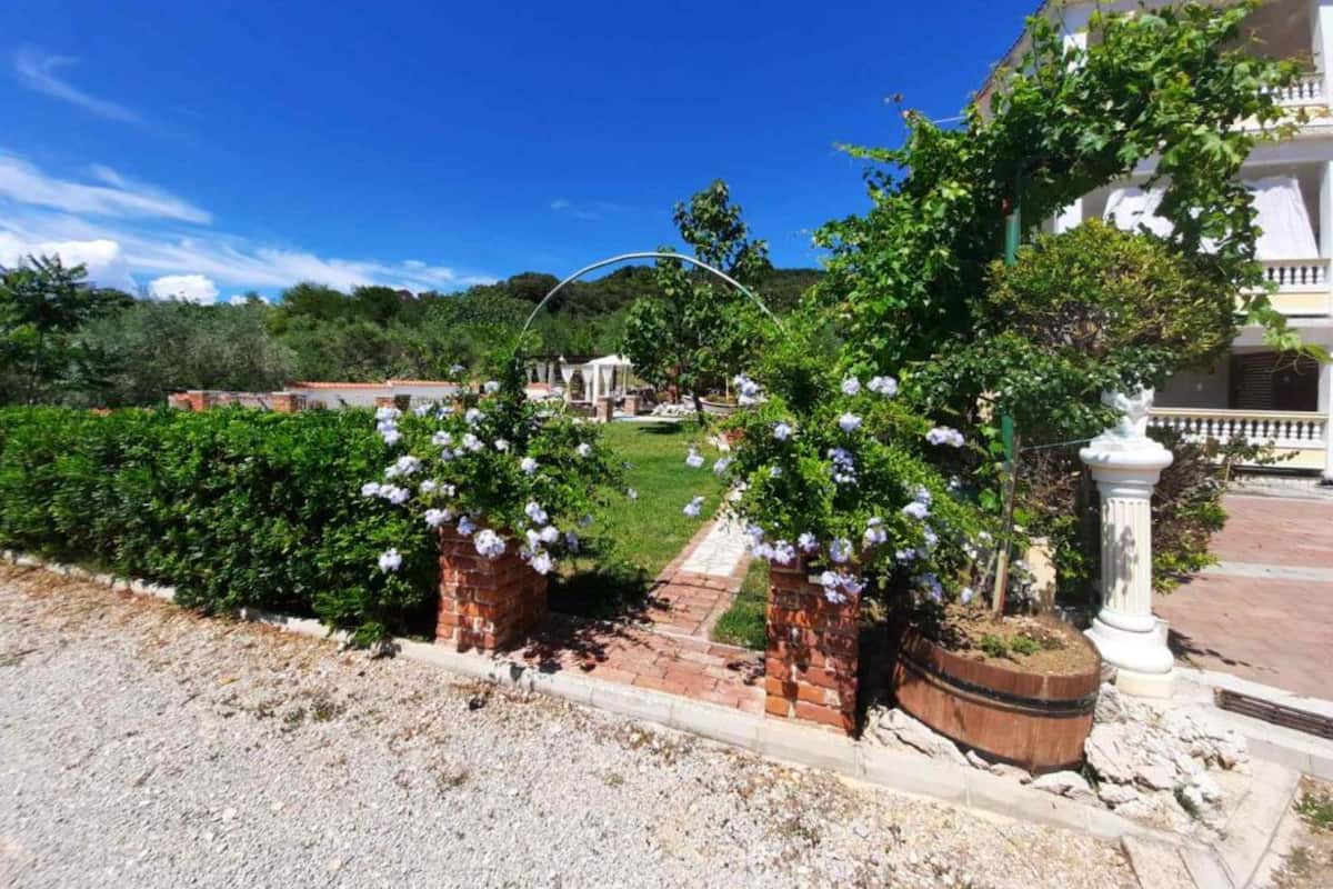 Un jardin avec un sentier menant à un bâtiment blanc doté d’un balcon.