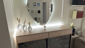 Ett rum med en rund spegel ovanför ett avlastningsbord, en soffa och en tv som står på en hylla.