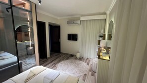 Een hotelkamer met een bed, een televisie, een spiegel, een klein tafeltje, een nachtkastje, een lamp, een raam en een deur.