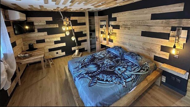 A bedroom with a bed, wooden ceiling, and wall-mounted lights.