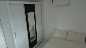 Une chambre à coucher comprenant un lit, une armoire et un appareil de climatisation.