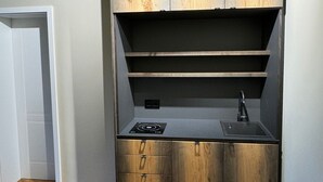 Kompakti keittiö, jossa on puukaapit, sisäänrakennettu liesi ja pesuallas.