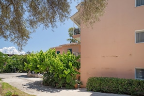 Ein Gebäude mit Balkon, gepflastertem Bereich und Baum.