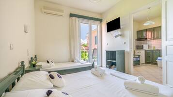 A hotel room with a bed, a TV, a kitchenette, and a balcony.