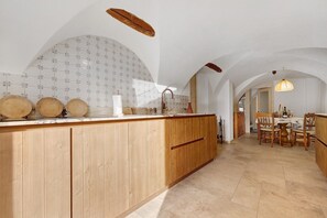 Una cocina con armarios de madera, salpicadero de azulejos y comedor con mesa y sillas.