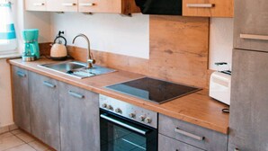Una cocina con armarios de madera, un fregadero, un hervidor, un tostador y un horno.