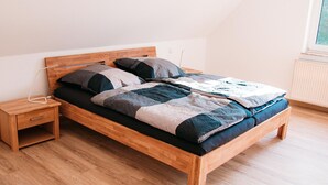 Una cama individual con estructura de madera, una mesita de noche y un enchufe en la pared.