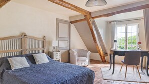 Ein Schlafzimmer mit einem Bett, einem Schreibtisch, einem Stuhl, einer Lampe und einem Fenster mit Vorhängen.