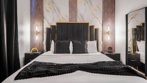 A modern bedroom with a large bed, a headboard with vertical slats, bedside tables with lamps, and a large mirror. - Luxury 3BR Home at The Hub Near Disney (Kissimmee)