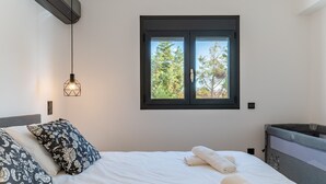 Een slaapkamer met een bed, kussens, een raam en een verwarming.