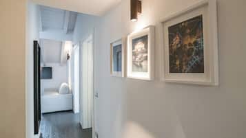 A hallway with framed artwork on the walls, a sofa, and a ceiling light fixture.