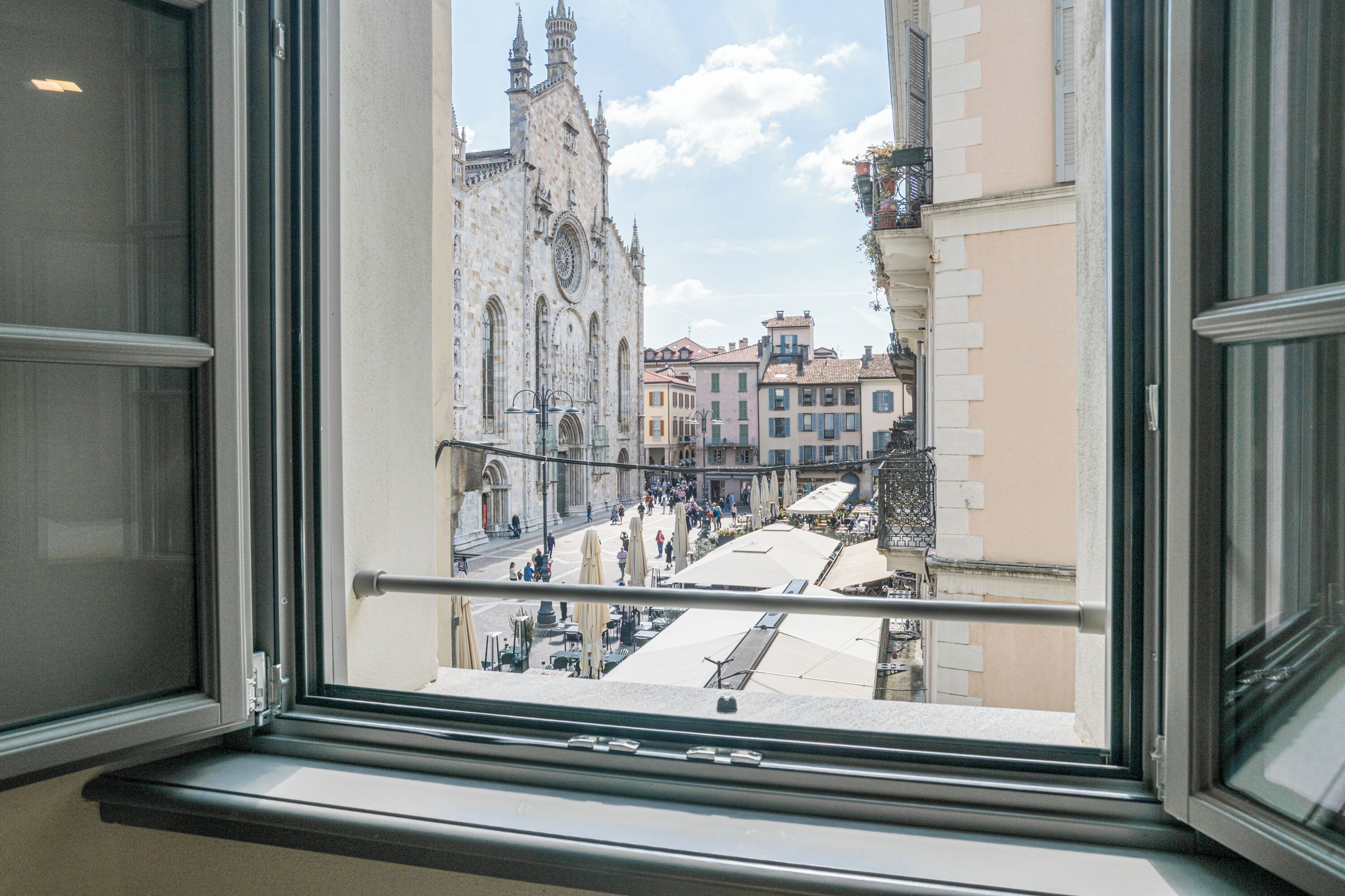 A view from a window overlooking a historic church and a bustling street with cafes.