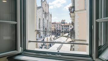 A view from a window overlooking a historic church and a bustling street with cafes.