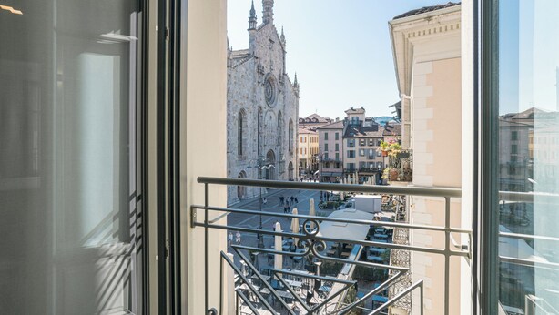 A view from a balcony with a wrought iron railing, overlooking a historic church and surrounding buildings. - Palazzo La Cortesella (Como)