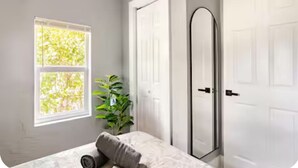 A bedroom with a bed, a window with a view of trees, a plant, and a door. - MIAMI-close to downtown/Wynwood/mid-town/Brickell (Miami)