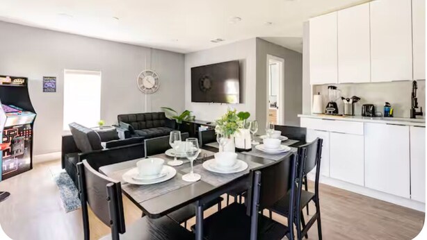 A modern living room with a dining table set for four, a sofa, and a flat-screen TV. - MIAMI-close to downtown/Wynwood/mid-town/Brickell (Miami)