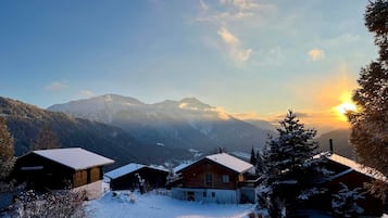 Eine verschneite Berglandschaft mit Holzhütten und blauem Himmel.