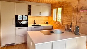 Una cucina moderna con mobili bianchi, un'isola centrale, una finestra e travi a vista in legno.