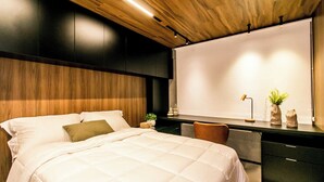 A modern bedroom with a large bed, a desk, and a large window. - Apartamento Climatizado com Garagem em Alphaville (Barueri)