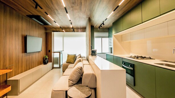 A modern kitchen with a built-in island, green cabinets, and a wooden ceiling. - Apartamento Climatizado com Garagem em Alphaville (Barueri)