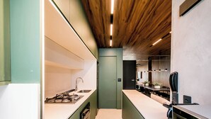 A modern kitchen with a central island, built-in appliances, and a wooden ceiling. - Apartamento Climatizado com Garagem em Alphaville (Barueri)