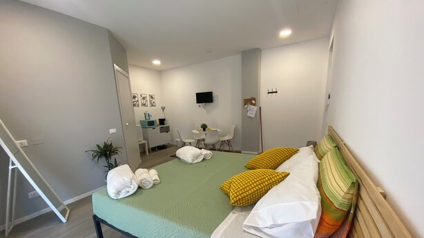 Una camera da letto ordinata con un letto, cuscini, una scrivania e una sedia.