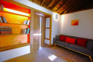 A room with a wooden floor, a grey sofa with red cushions, a bookshelf with books, and a wooden ceiling. - Luxury villa with heated pool and exceptional sea and canyon views, (Barlovento)