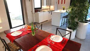 A modern kitchen with white cabinets, a dining area with a red tablecloth, and a large potted plant. - Luxury villa with heated pool and exceptional sea and canyon views, (Barlovento)