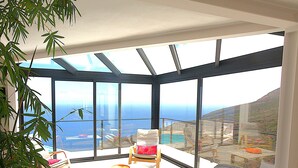 A modern room with large windows, a sofa, a chair, and a dining table. - Luxury villa with heated pool and exceptional sea and canyon views, (Barlovento)