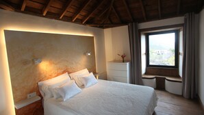 A bedroom with a large bed, a nightstand, a dresser, a window with a view, and a wooden ceiling. - Luxury villa with heated pool and exceptional sea and canyon views, (Barlovento)