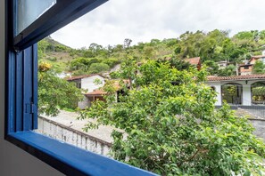 A view from a window overlooking a hillside with houses and a gazebo. - Piscina Lareira e Natureza Incr vel - Petr Polis (Petrópolis)