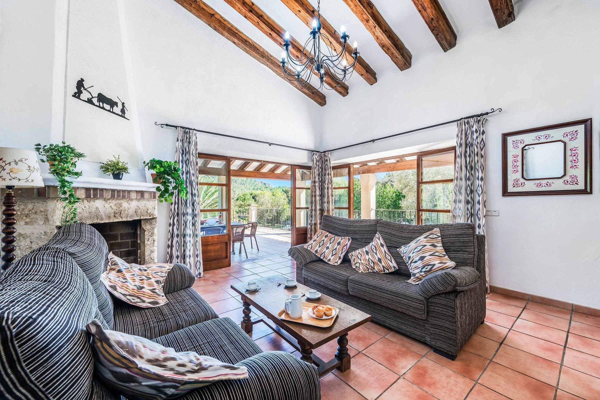 Ampla sala de estar com lareira, dois sofás, uma mesa de centro e grandes janelas com vista para o exterior.