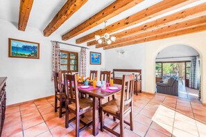 A dining area with wooden tables and chairs, a ceiling fan, and artwork on the walls. - Finca Cas Tomas | Cala San Vicente | Traditional charm and mountain views |. (Pollensa)
