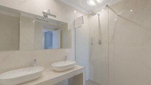 Un baño moderno con dos lavamanos, una ducha y un espejo.