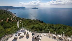 A terrace with outdoor seating and a scenic ocean view. - Hotiday Pozzuoli (Pozzuoli)