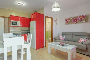 Ein kompakter Wohnbereich mit Küchenzeile, Essbereich und einer Sitzecke mit Sofa und Couchtisch.
