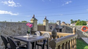 Un patio con muros de piedra, una mesa con sillas y una barandilla decorativa.