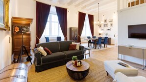 A spacious living room with a sofa, a round coffee table, and a television. - Apartment 'Fewo Saalstube, Adolphsburg' with Shared Garden and Wi-Fi (Kirchhundem)